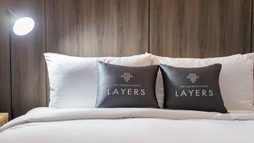A bed with white bedding and two pillows with a logo and text reading "The Luxurious Hotel Layers".