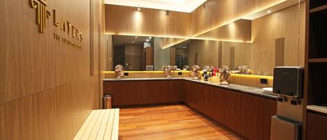 A modern hotel kitchen with wooden flooring, a wooden bench, and a refrigerator.