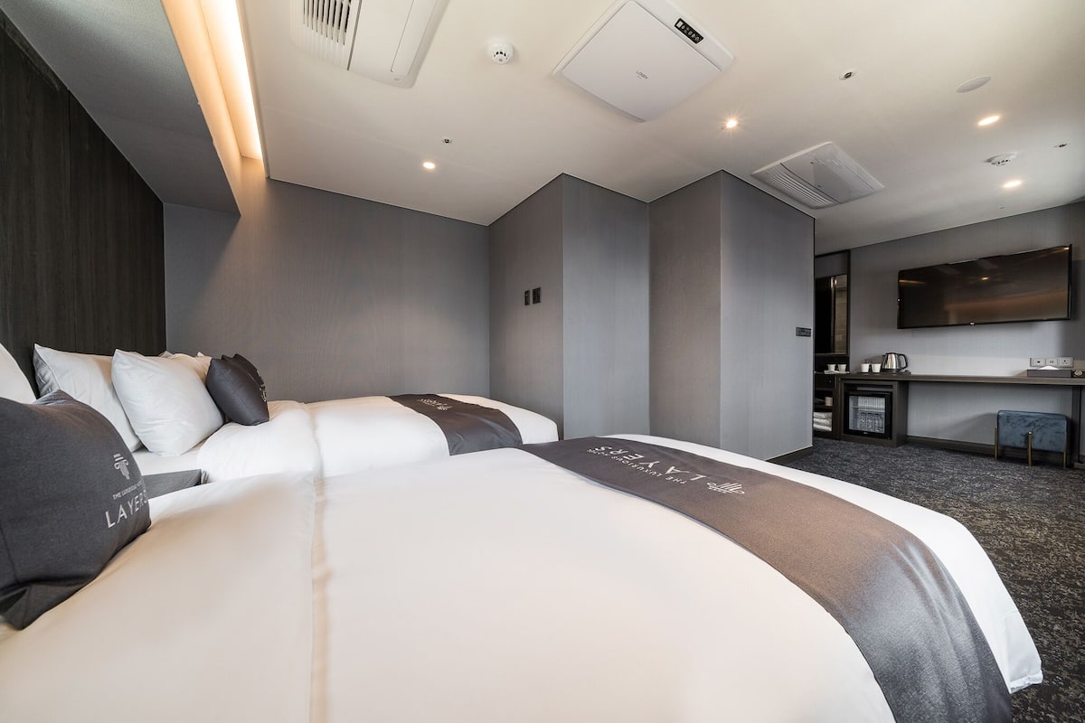 A modern hotel room with a large bed, a desk, and a flat-screen TV.