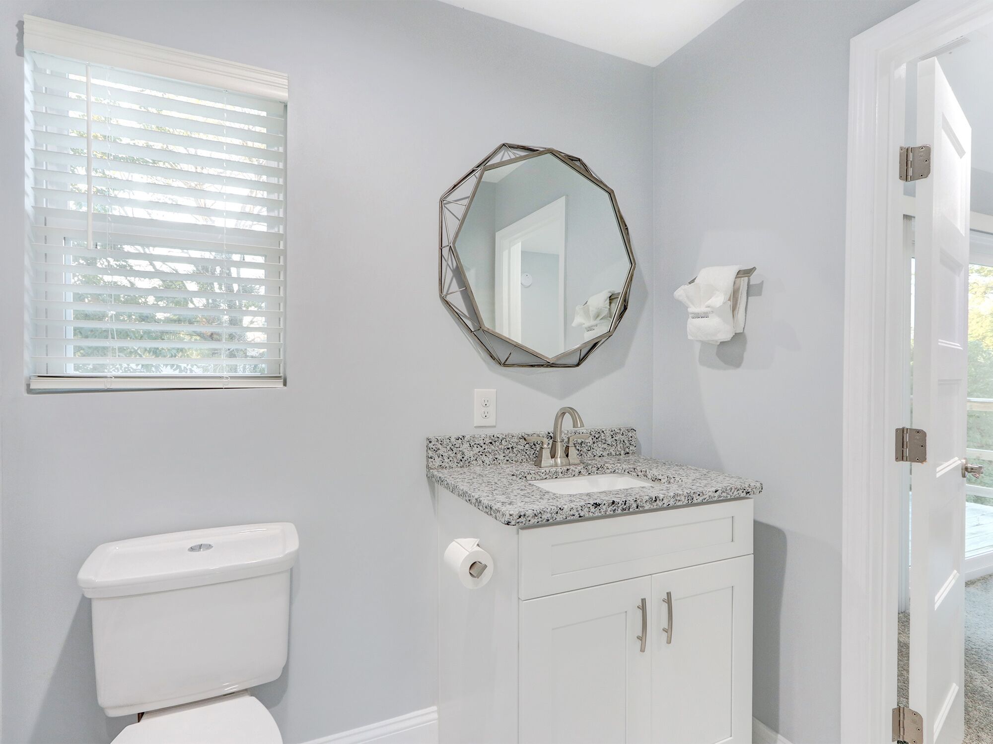 A bathroom with a toilet, sink, and mirror.