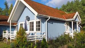 A blue wooden house with a red-tiled roof, white trim, and a porch with white chairs. - Cosy apartment in villa for 6 people with WIFI, TV and terrace (Userin)