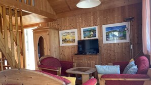 A wooden cabin interior with a TV, wooden furniture, and framed artwork on the walls. - Cosy apartment in villa for 6 people with WIFI, TV and terrace (Userin)