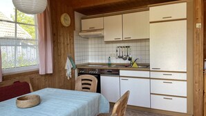 A cozy kitchen with wooden cabinets, a sink, and a dining area with a table and chairs. - Cosy apartment in villa for 6 people with WIFI, TV and terrace (Userin)