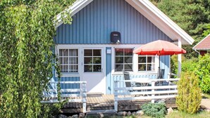 A blue house with a white porch, a red umbrella, and a satellite dish. - Cosy apartment in villa for 6 people with WIFI, TV and terrace (Userin)