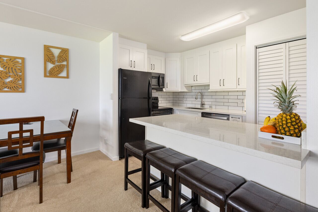 A modern kitchen with white cabinets, a black refrigerator, and a central island with stools.