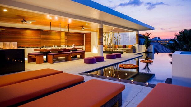 Un área de descanso al aire libre moderna con piscina, mobiliario y bar.