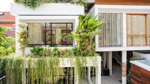 Un edificio moderno con jardín en el balcón, ventanas amplias y fachada de madera.
