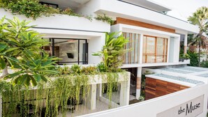 Un edificio moderno con fachada blanca, un atrio de cristal y un letrero que dice "the Muse".