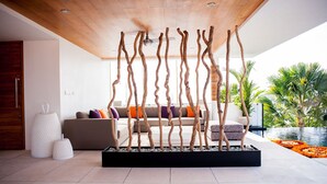 Una sala de estar moderna con techo de madera, un sofá con cojines de colores y una estructura decorativa de madera.