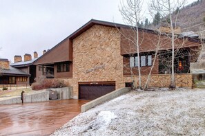 Un bâtiment en pierre avec une pancarte indiquant « Cour », un garage et un sol recouvert de neige.