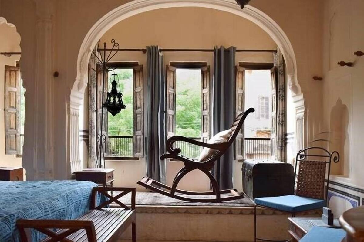 A room with a large arched doorway, a rocking chair, a blue sofa, and a wooden table.