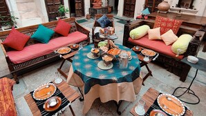 Ein traditioneller Innenhof mit aufwendigen Holztüren, einem zentralen runden Esstisch und gemütlichen Sitzbereichen.