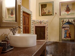 Un baño con un lavabo redondo, una puerta de madera y decoración en la pared.