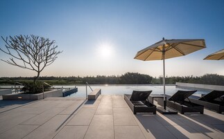 Una piscina al aire libre, sombrillas, sillones reclinables de piscina