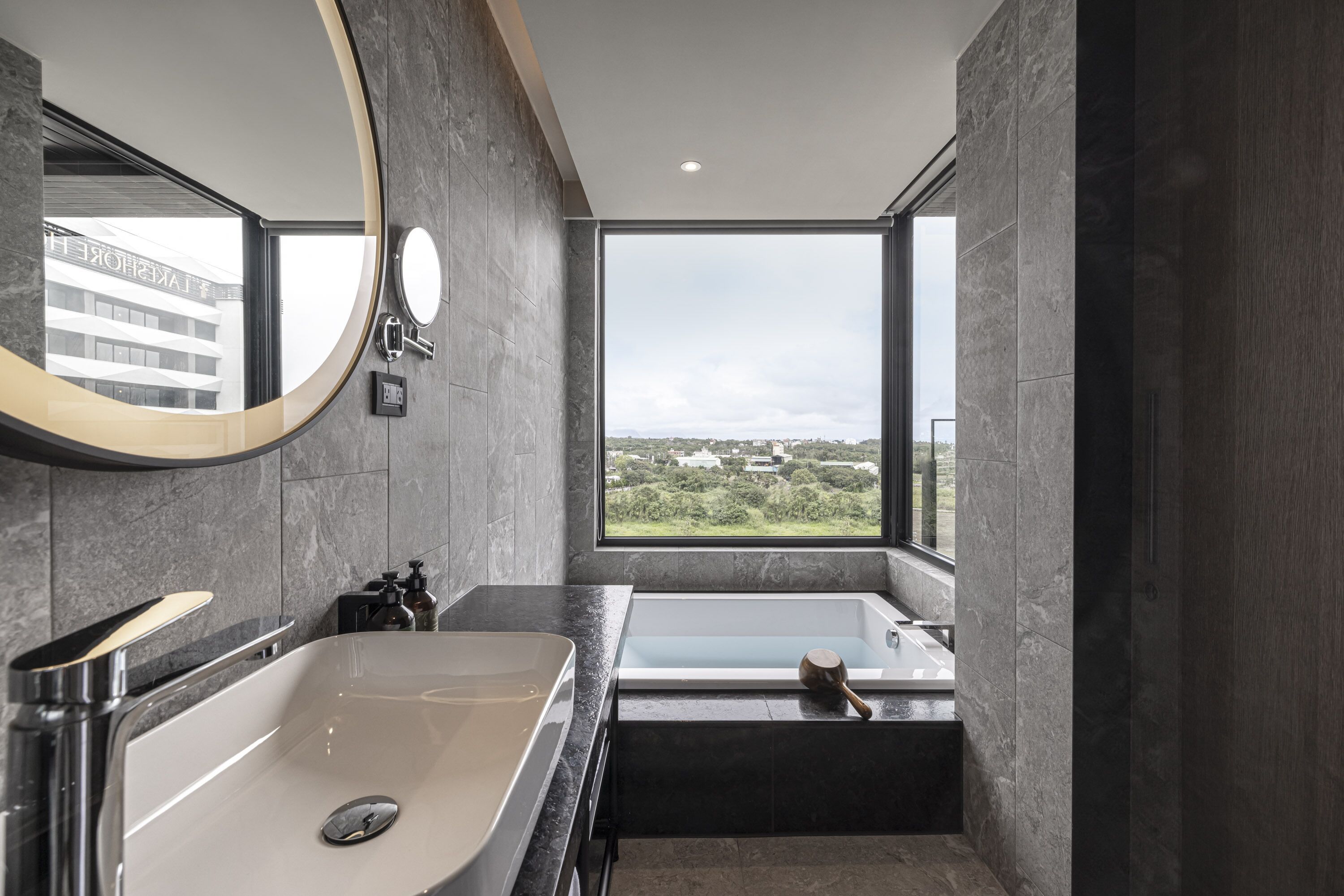 A modern bathroom with a large mirror, a sink, and a bathtub.