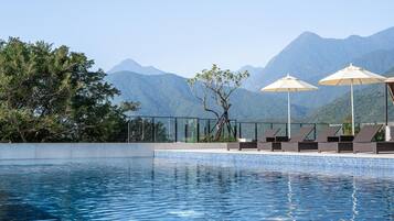 Una piscina al aire libre, sombrillas, sillones reclinables de piscina