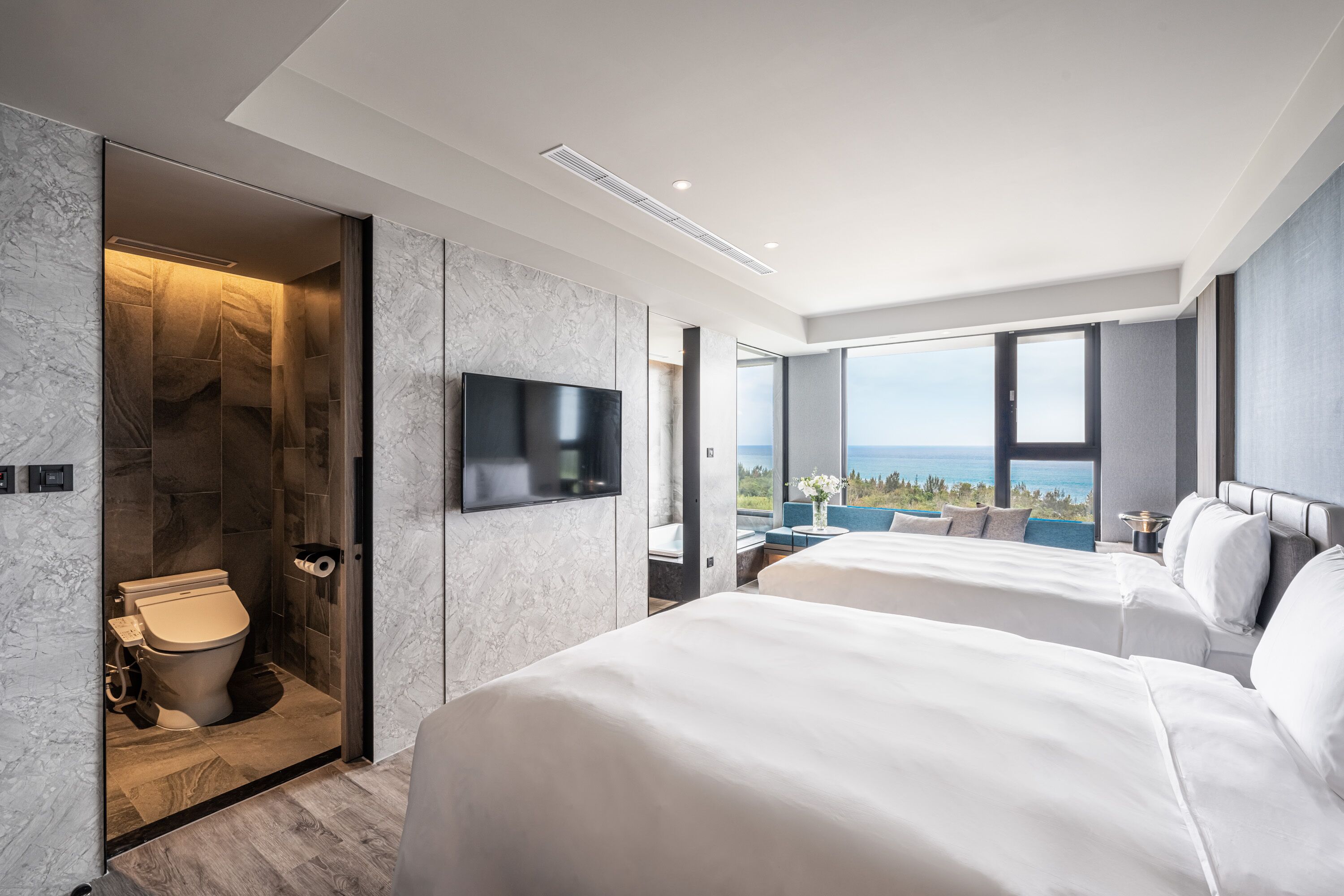 A modern hotel room with a large bed, a television, and a bathroom with a toilet and shower.