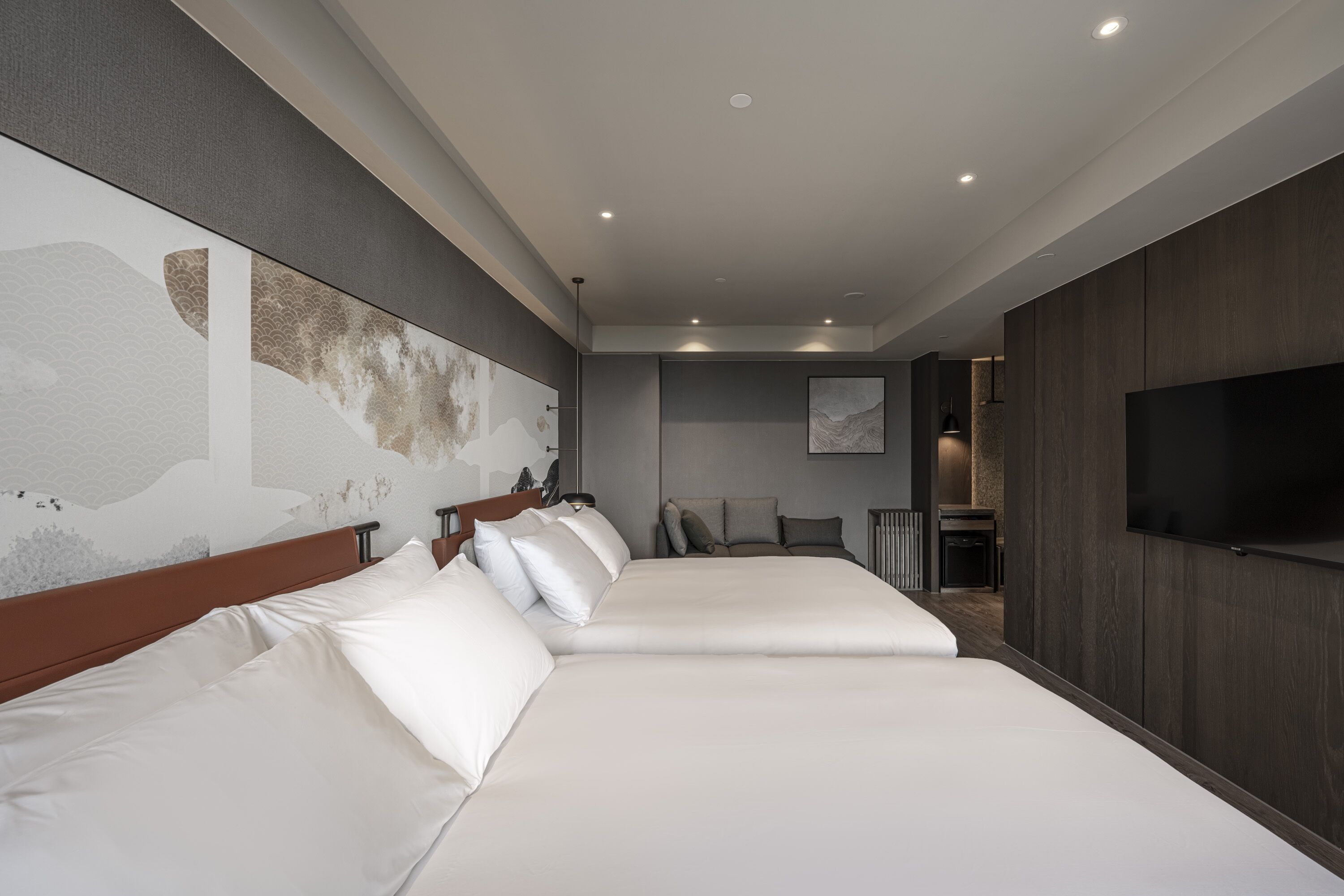 A hotel room with a large bed, a television, and a wall-mounted artwork.