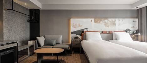 A modern hotel room with two beds, a sofa, a desk, and a large abstract painting on the wall.