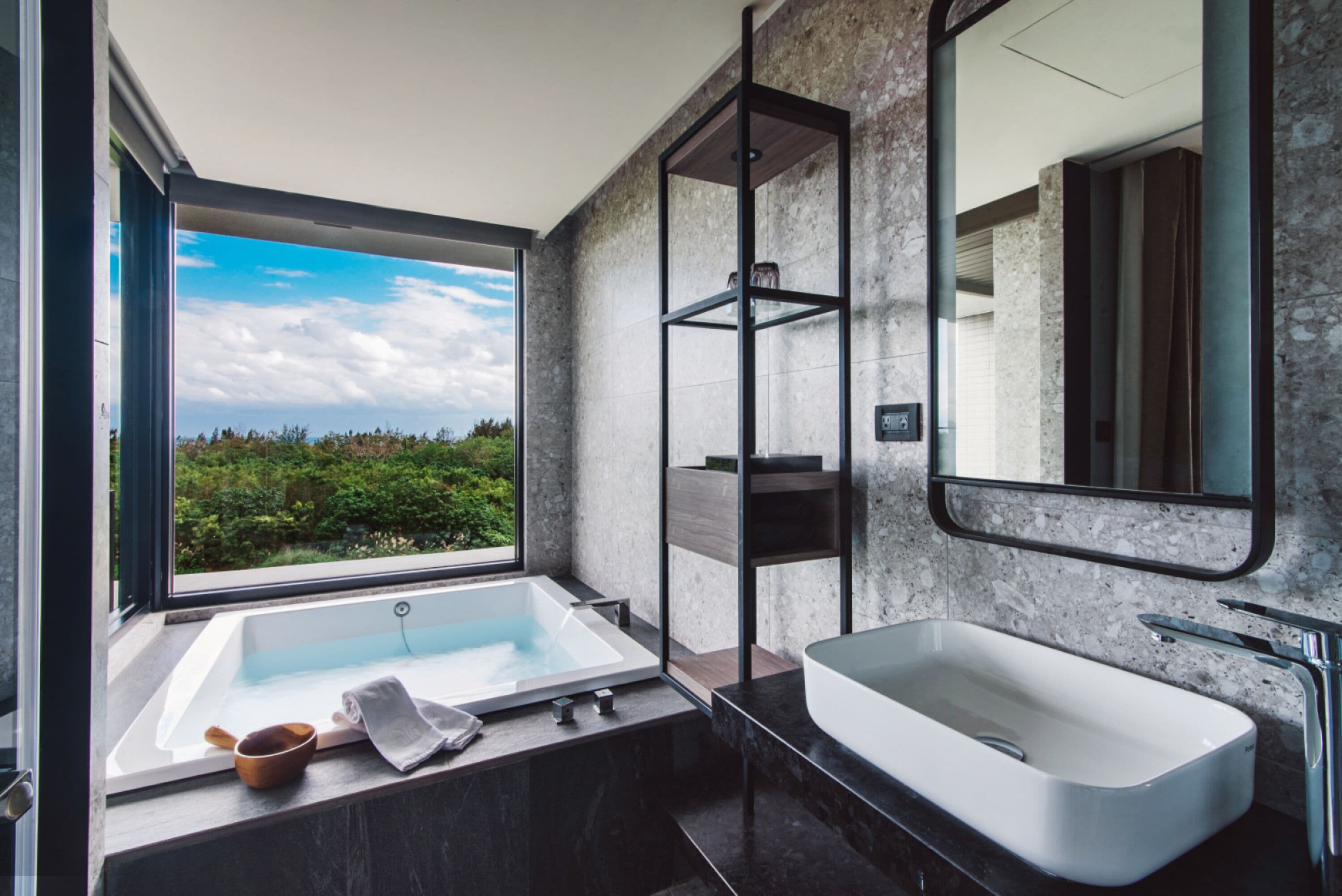 A modern bathroom with a large window, a freestanding bathtub, a rectangular sink, and a mirror.