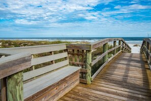 A wooden boardwalk leading to a beach with a clear view of the ocean.
