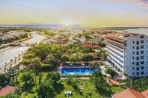 Un hôtel doté d’une piscine, d’une végétation luxuriante et offrant une vue sur l’eau.