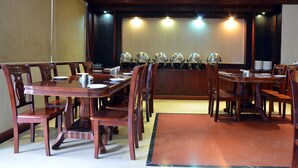 Une salle de conférence avec une longue table et des chaises, un écran de projection et une rangée de casques accrochés au mur.