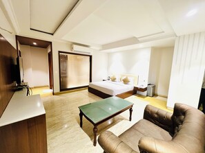A modern hotel room with a bed, a desk, a chair, and a small table.