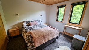 Un dormitorio con cama, mesitas de noche, un escritorio y una ventana.