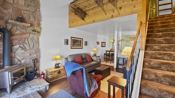 Ein gemütliches Wohnzimmer mit Kamin aus Stein, einer Couch, einem Couchtisch und einer Treppe zu einer weiteren Ebene.