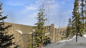 Ein verschneiter Weg führt zu einem Gebäude mit geneigtem Dach und Steinmauern.