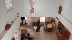 A spacious living area with a high ceiling, a dining table, sofas, and a wooden cabinet. - Exclusive duplex near Jaffa fishermen port and old city, Family (Tel Aviv)