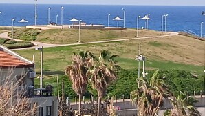 A coastal area with a paved walkway, palm trees, and beach umbrellas. - Exclusive duplex near Jaffa fishermen port and old city, Family (Tel Aviv)