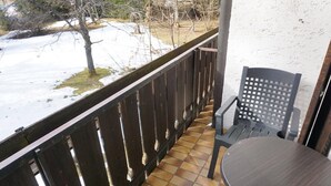 A balcony with a wooden railing, a chair, and a table. - Pension & Fewos Fuchs (Mauth)