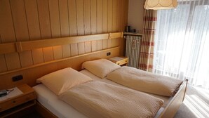 A double bed with a wooden headboard and two bedside tables, each with a lamp. - Pension & Fewos Fuchs (Mauth)