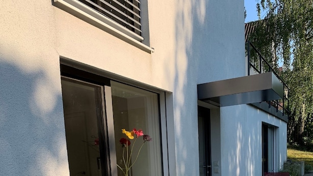 A modern building with a large window displaying flowers. - F80-Die FEINE Ferienwohnung (Regensburg)