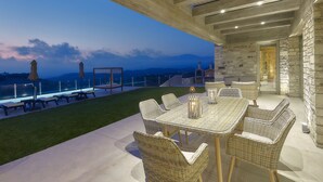 Un patio exterior con muebles de mimbre y una mesa, con vistas a un paisaje idílico.