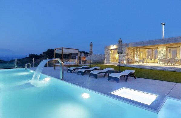 A swimming pool with lounge chairs and a stone building with a chimney.