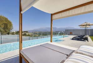 A poolside area with a view of mountains, lounge chairs, and a water feature.