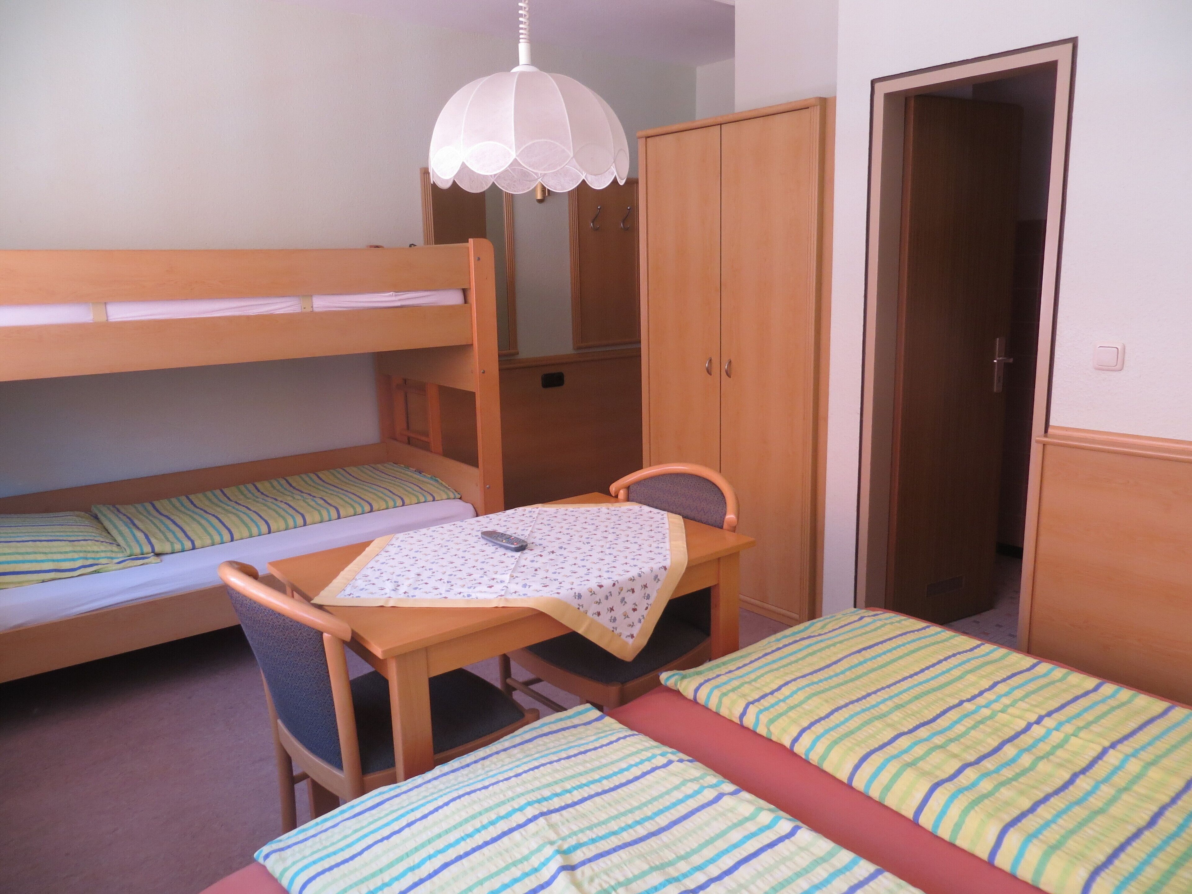 Un dormitorio con literas, una mesa de madera y una silla.