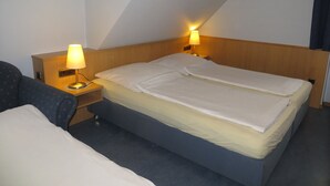 A hotel room with a single bed, two bedside lamps, a wooden headboard, and a small bedside table. - Rotes Ross Burghaslach (Burghaslach)