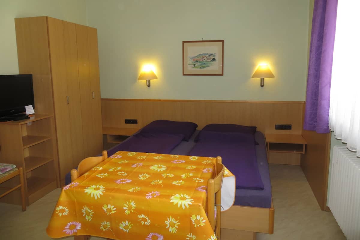 A hotel room with two beds, a TV, and two wall lamps.