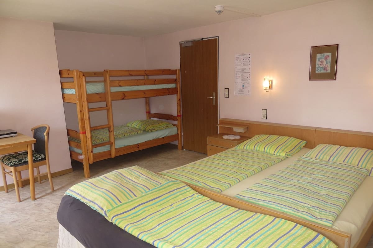 A room with bunk beds, a desk, and a chair.
