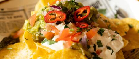 Nachos cubiertos de guacamole, crema agria, tomates picados y jalapeños en rodajas.