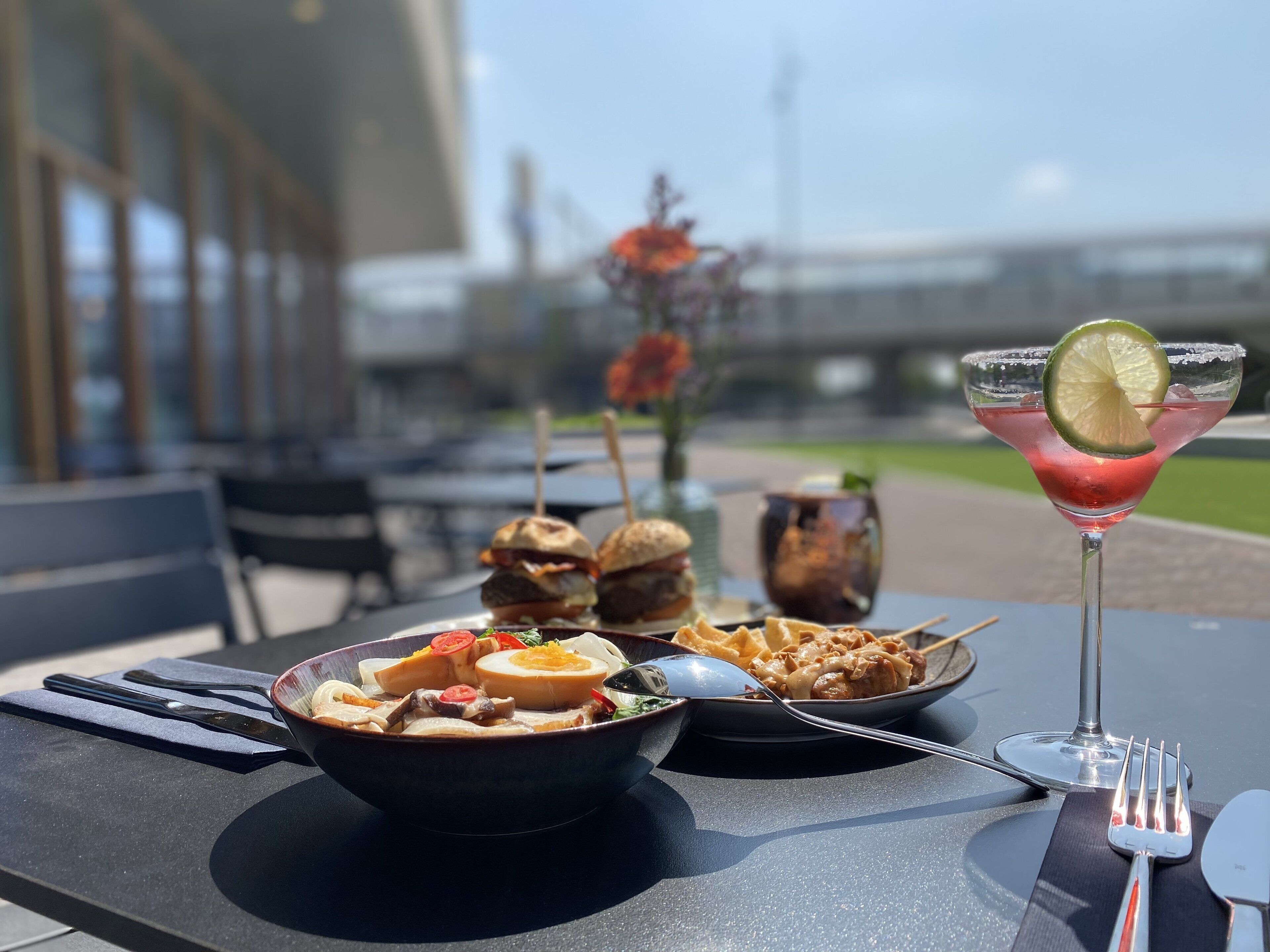 A table set with a bowl of food, a plate with a drink, and a martini glass with a lime garnish.