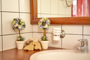 Ein Badezimmer mit zwei Topfpflanzen, einem Waschbecken und einem Spiegel.