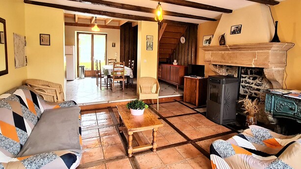 Ein gemütliches Wohnzimmer mit Kamin, Holzbalken und einem Essbereich mit Tisch und Stühlen.