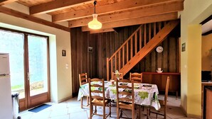 Ein Essbereich mit Holztisch und -stühlen, einer Holztreppe und einem Kühlschrank.