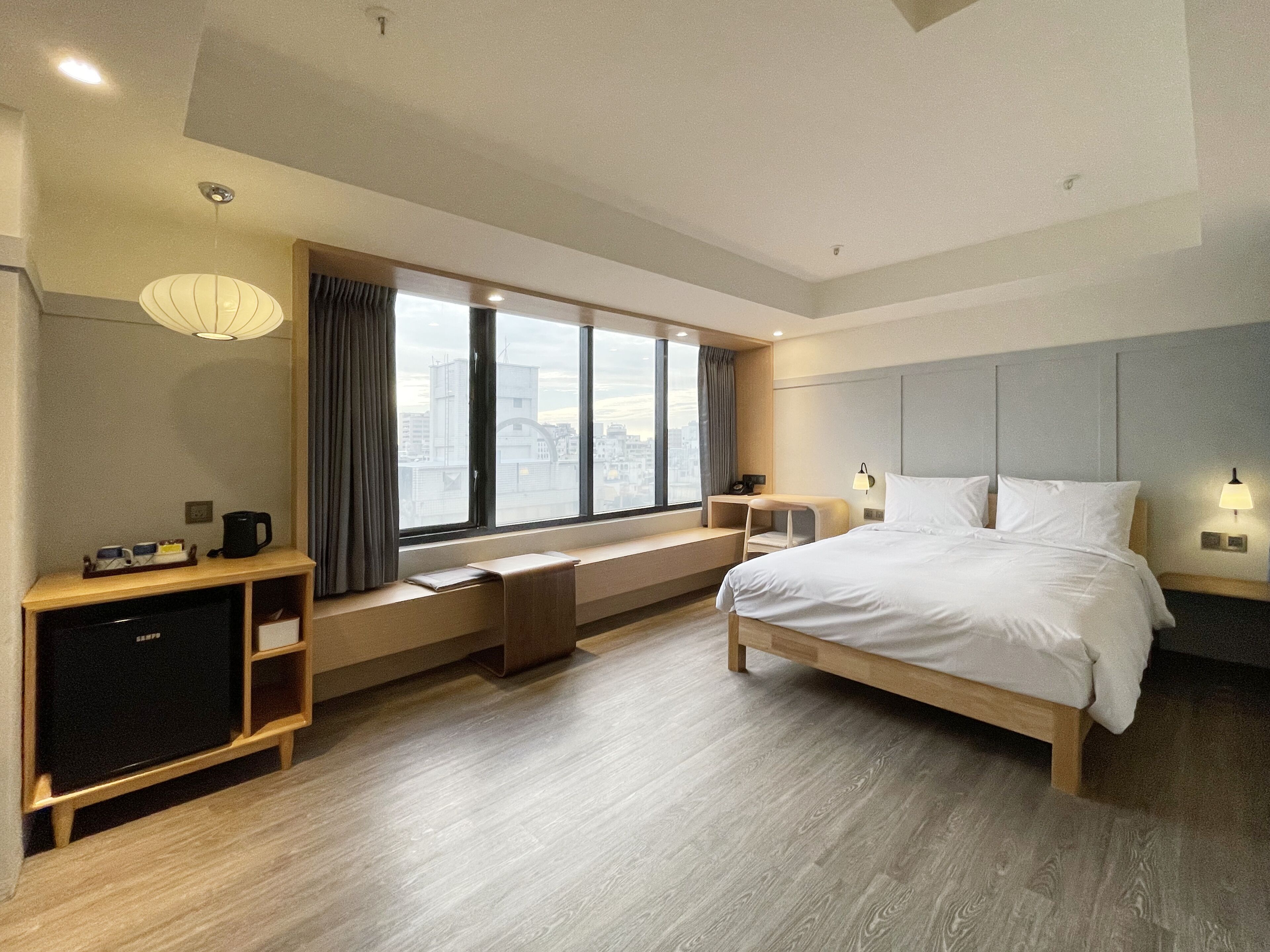 Habitación de hotel moderna con una cama grande, un escritorio y una ventana con vistas a la ciudad.