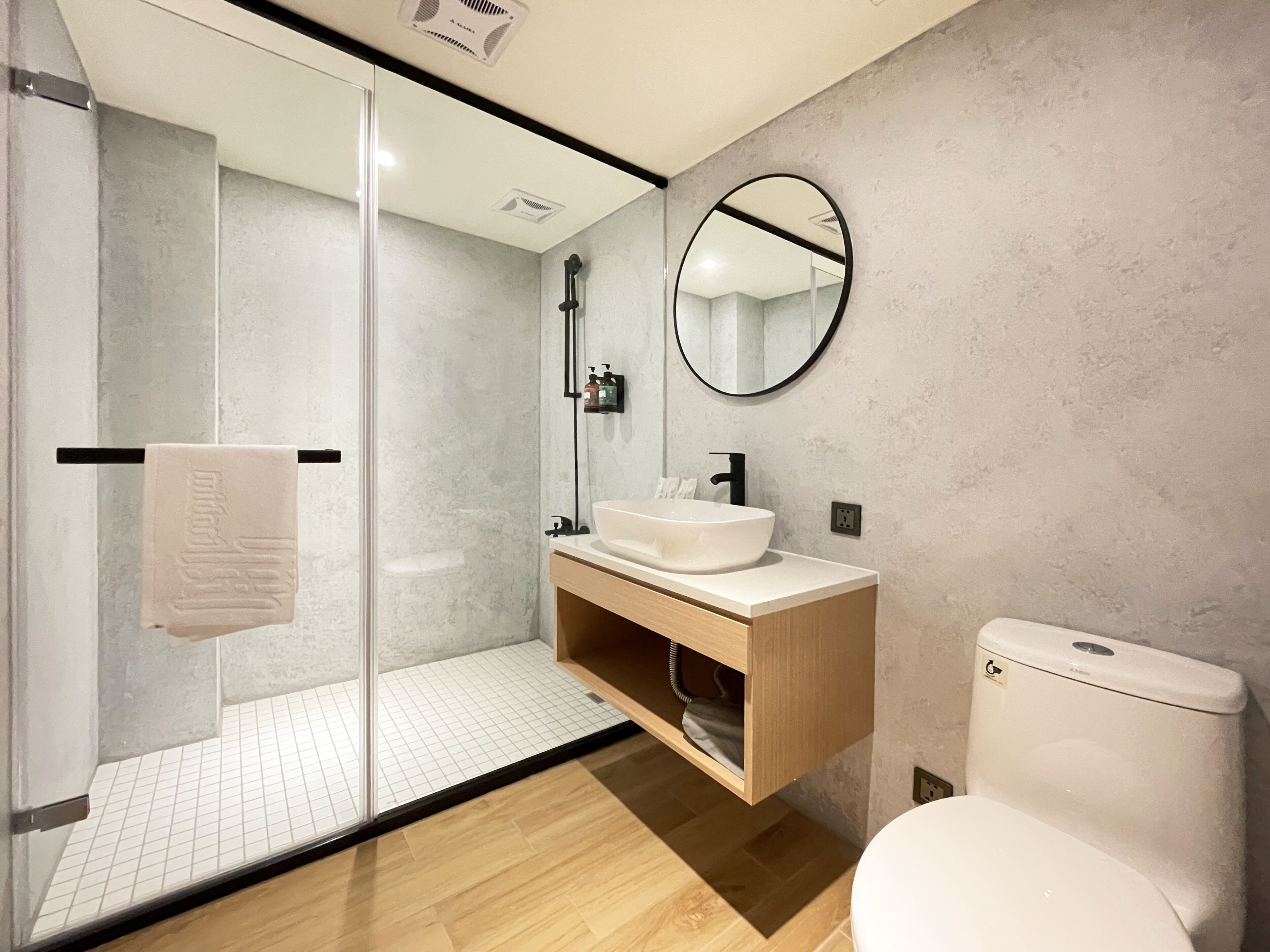 A modern bathroom with a glass shower enclosure, a white sink, and a toilet.